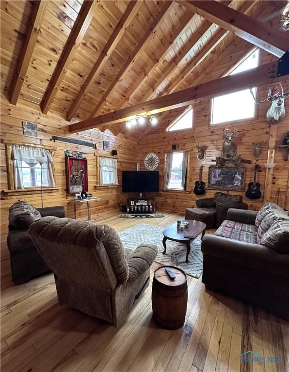 living room with high vaulted ceiling, wooden walls, wood ceiling, beamed ceiling, and wood-type flooring