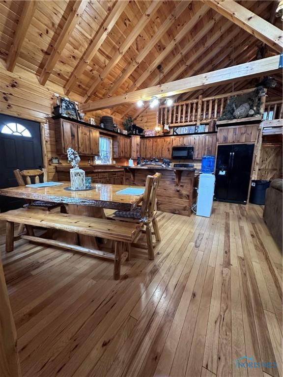 dining room with high vaulted ceiling, wood walls, wooden ceiling, and light wood finished floors