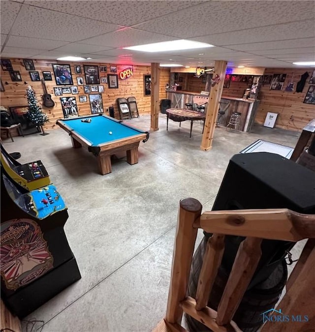 game room with concrete flooring, billiards, a paneled ceiling, and wooden walls