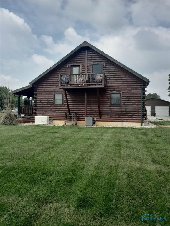 back of house with central air condition unit, a balcony, log exterior, and a yard