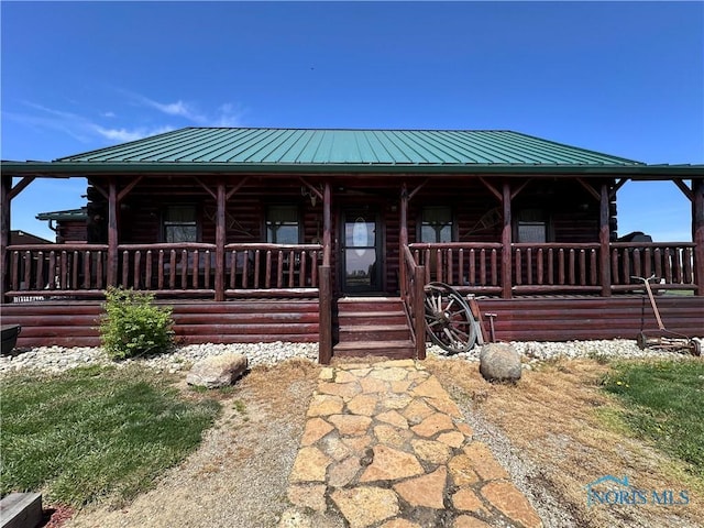 cabin with log siding, covered porch, and metal roof