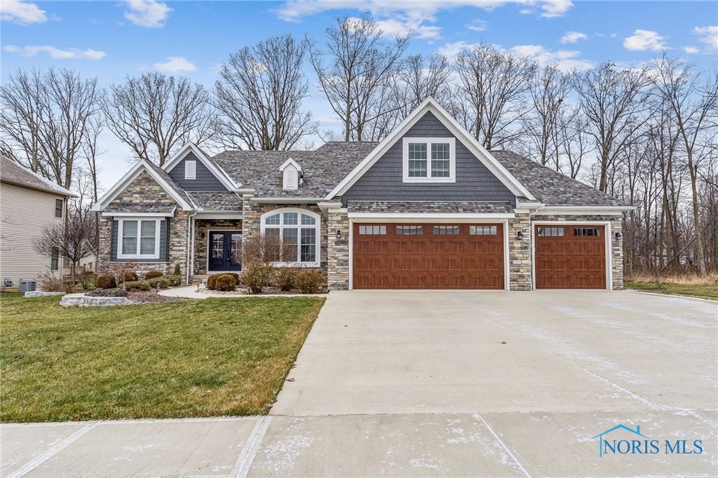 craftsman inspired home with a garage, central air condition unit, and a front lawn