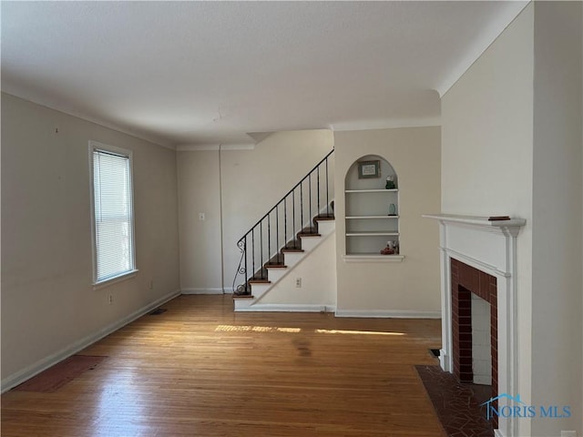 unfurnished living room with crown molding, hardwood / wood-style floors, and built in features