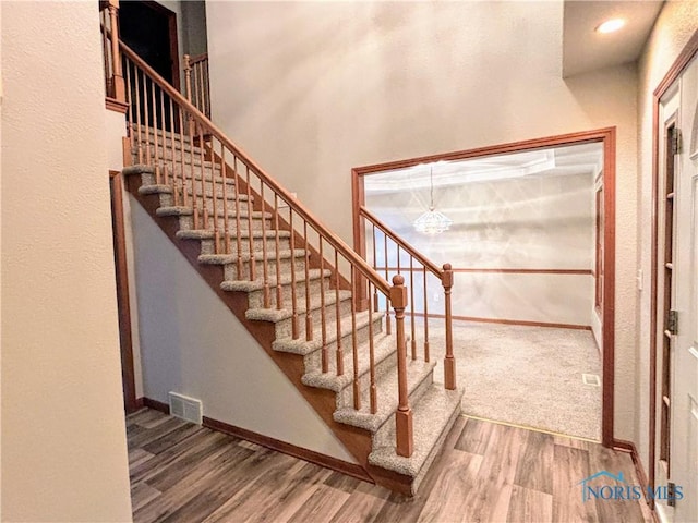 staircase featuring wood-type flooring and a high ceiling