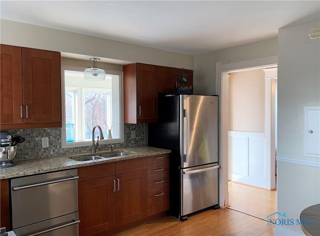 kitchen featuring decorative backsplash, appliances with stainless steel finishes, light stone counters, and sink