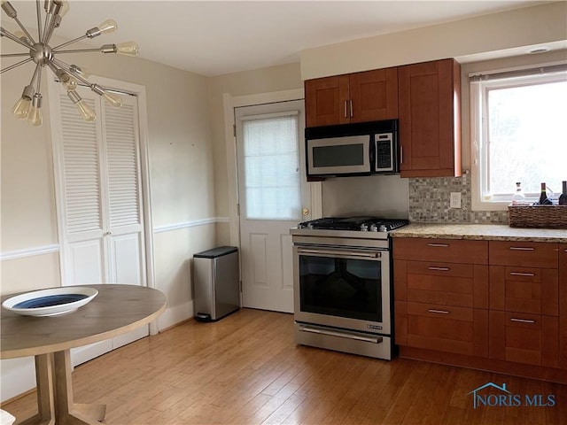 kitchen with backsplash, stainless steel gas stove, and light wood-type flooring