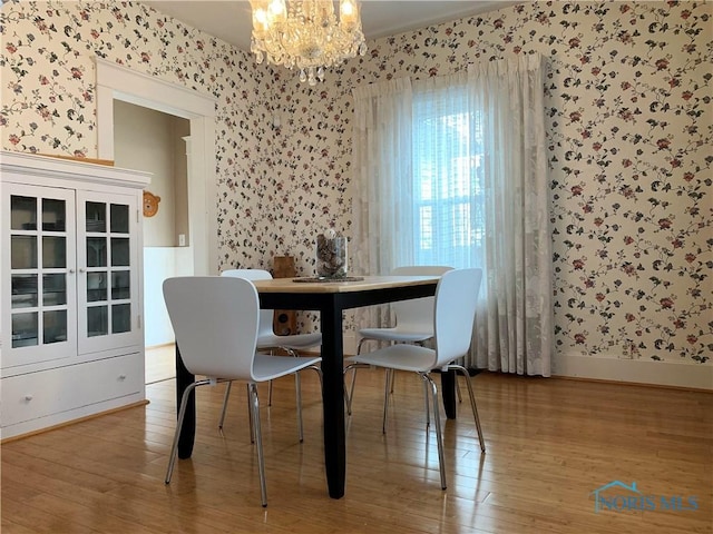 dining area with hardwood / wood-style flooring and an inviting chandelier