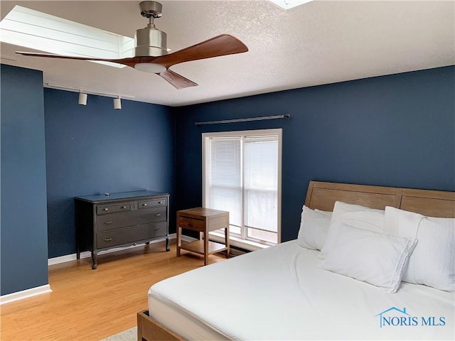 bedroom with ceiling fan, hardwood / wood-style floors, and a textured ceiling