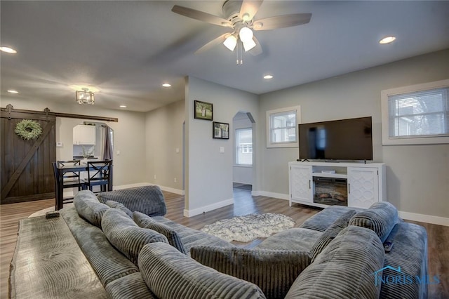 living room featuring a barn door, hardwood / wood-style flooring, and ceiling fan