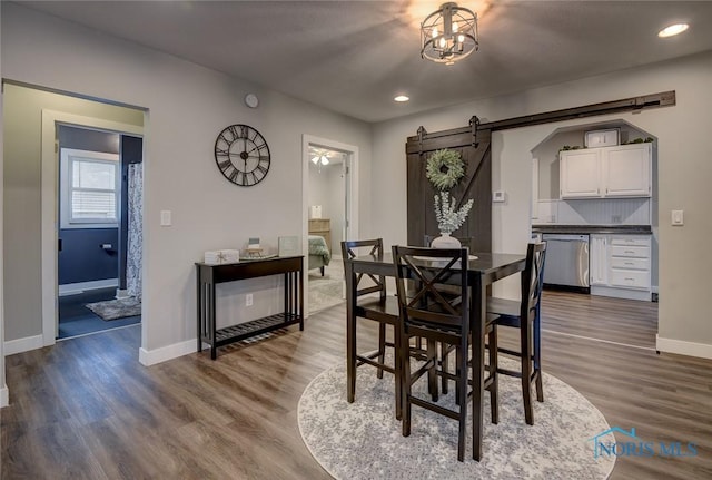 dining space with a barn door and hardwood / wood-style flooring