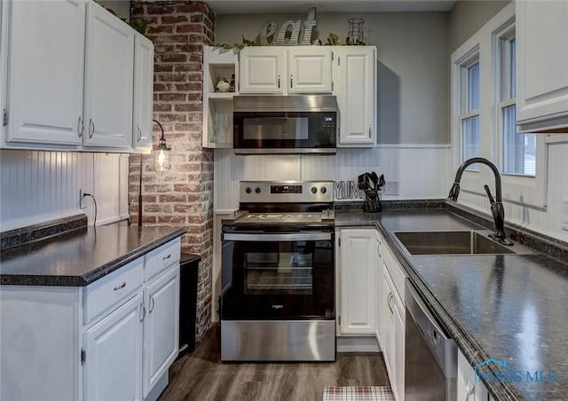 kitchen featuring sink, dark wood-type flooring, brick wall, white cabinets, and appliances with stainless steel finishes