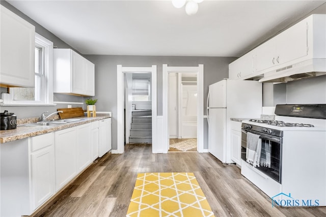 kitchen featuring white cabinets, light hardwood / wood-style floors, white appliances, and sink