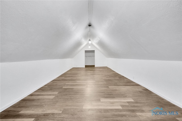 bonus room with vaulted ceiling, hardwood / wood-style floors, and a textured ceiling