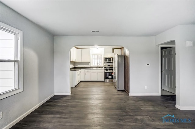 kitchen featuring appliances with stainless steel finishes, white cabinetry, dark wood-type flooring, and sink