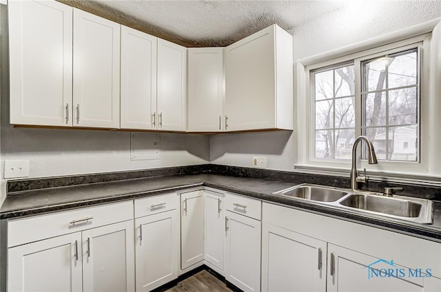 kitchen featuring a textured ceiling, white cabinetry, and sink