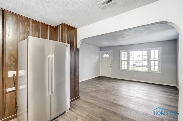 kitchen with high end fridge, light hardwood / wood-style floors, and a textured ceiling