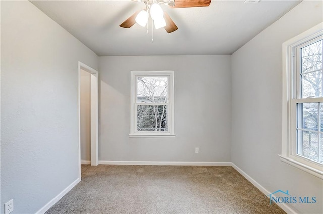 carpeted spare room featuring ceiling fan and a healthy amount of sunlight