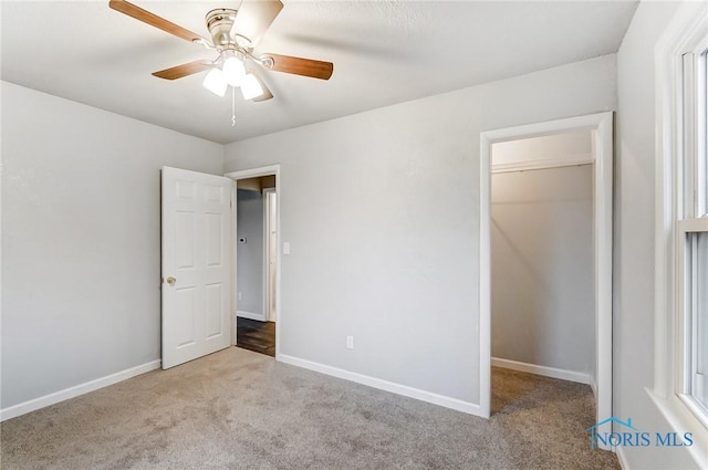 unfurnished bedroom featuring ceiling fan, light colored carpet, a spacious closet, and a closet