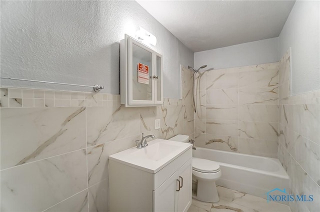 full bathroom with vanity, tiled shower / bath combo, toilet, and tile walls