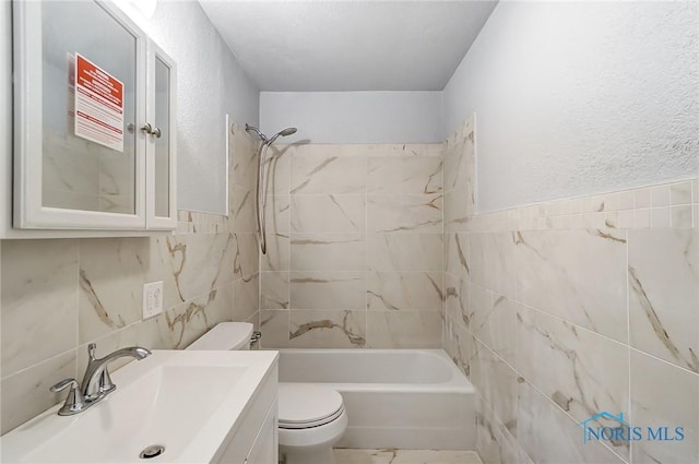 full bathroom with shower / bathtub combination, vanity, toilet, and tile walls