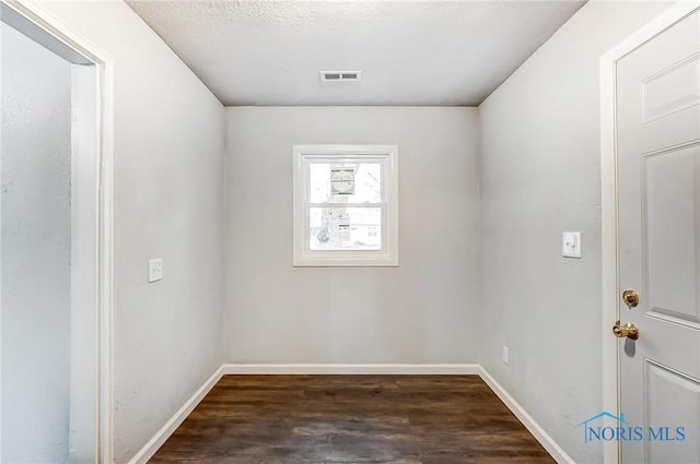 spare room featuring a textured ceiling and dark hardwood / wood-style floors