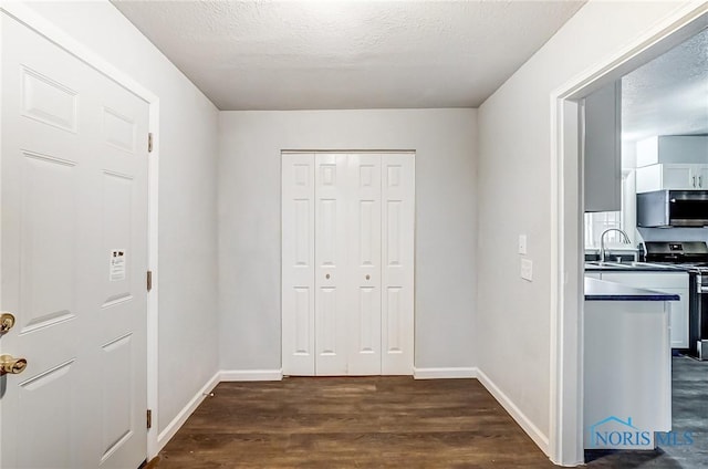 hall featuring a textured ceiling, dark hardwood / wood-style floors, and sink