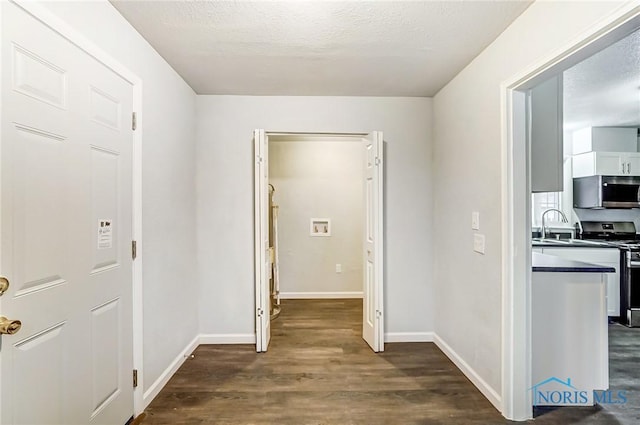 hallway featuring a textured ceiling, dark hardwood / wood-style floors, and sink