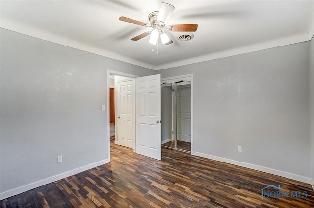 unfurnished bedroom with ceiling fan, dark wood-type flooring, and a closet