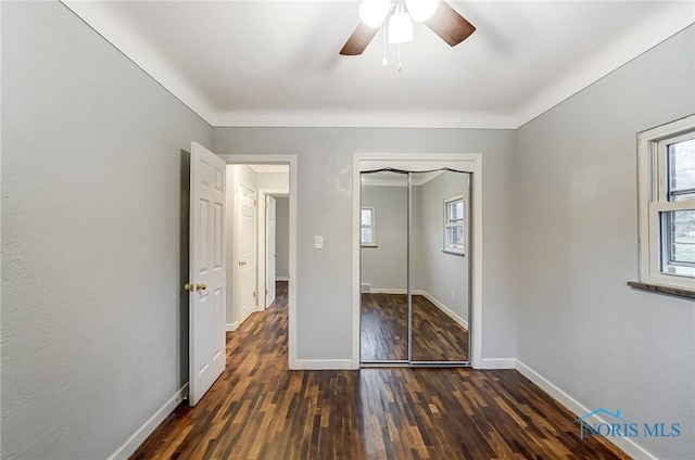 unfurnished bedroom with ceiling fan, a closet, and dark wood-type flooring