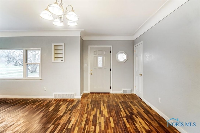 foyer featuring ornamental molding, dark wood-type flooring, and a chandelier