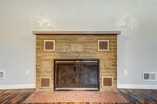 interior details featuring a stone fireplace and wood-type flooring