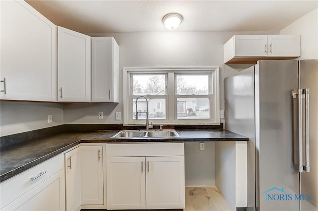 kitchen with white cabinets, light tile patterned floors, sink, and high quality fridge