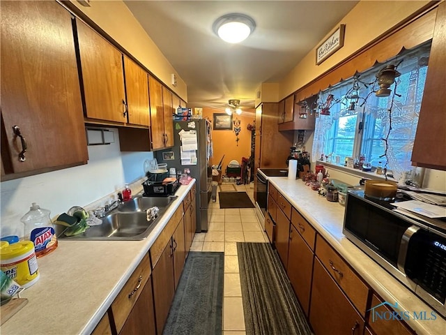 kitchen with sink, electric range oven, and light tile patterned flooring