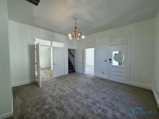 unfurnished bedroom with dark colored carpet and a chandelier