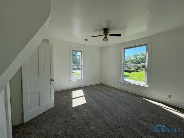 bonus room with ceiling fan and dark colored carpet