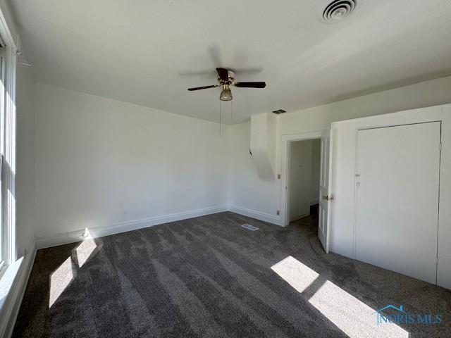 interior space with dark colored carpet and ceiling fan