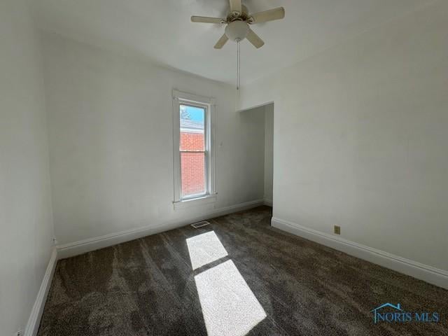 empty room featuring dark colored carpet and ceiling fan