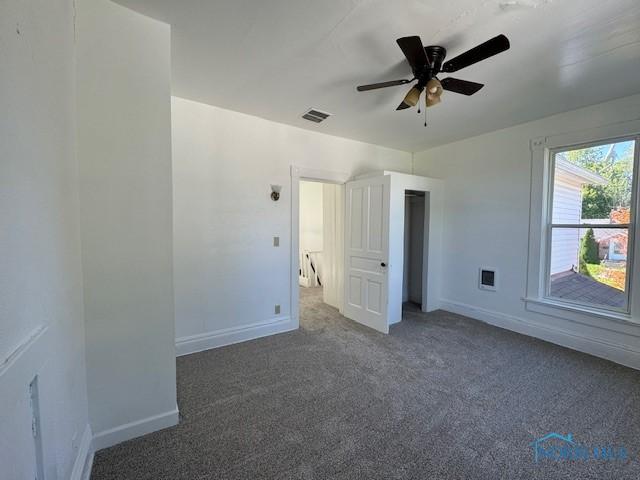 unfurnished bedroom featuring ceiling fan and dark carpet