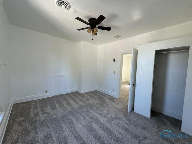 unfurnished bedroom featuring ceiling fan and dark carpet