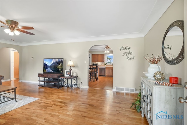 living room featuring wood-type flooring, ceiling fan, and crown molding