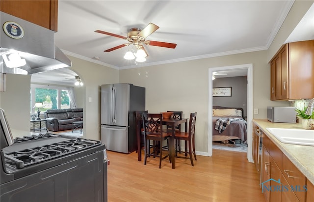 kitchen with range with gas stovetop, crown molding, exhaust hood, and stainless steel refrigerator