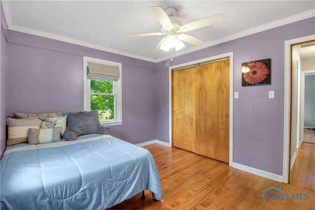 bedroom with light wood-type flooring, a closet, ceiling fan, and ornamental molding