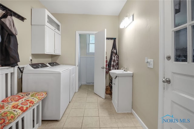 washroom featuring separate washer and dryer, sink, light tile patterned floors, and cabinets