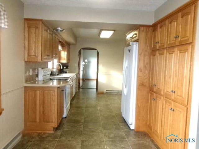 kitchen with sink, white appliances, baseboard heating, and backsplash