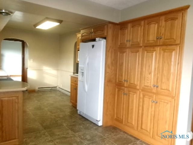 kitchen with baseboard heating and white fridge with ice dispenser