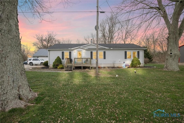 view of front facade featuring a lawn and a wooden deck