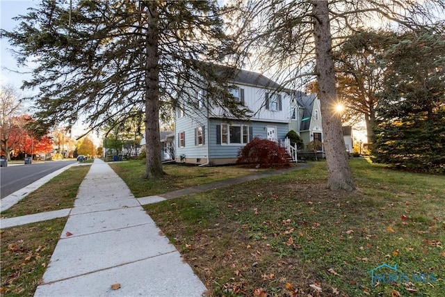 property exterior at dusk featuring a lawn