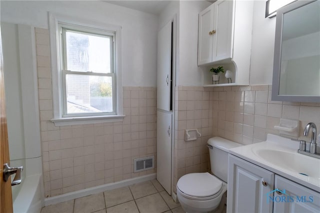 bathroom with tile patterned floors, vanity, tile walls, toilet, and a bathing tub