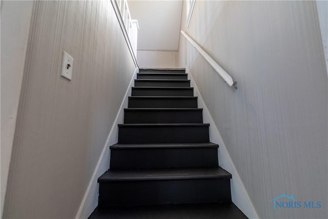 stairway featuring wooden walls