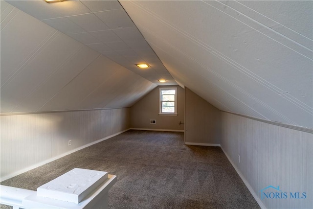 bonus room with lofted ceiling and dark colored carpet